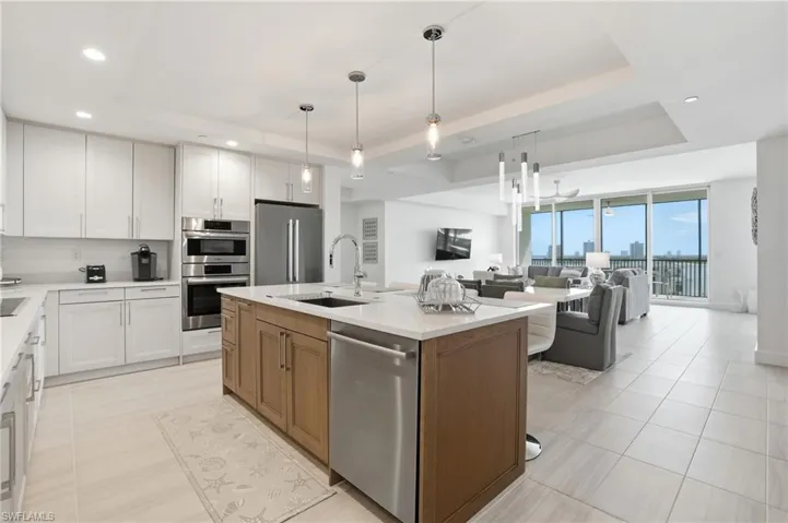 Kitchen featuring a tray ceiling, white cabinets, open floor plan, appliances with stainless steel finishes, and recessed lighting - Virtually Edited Image