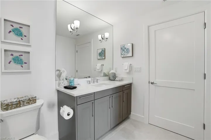 bathroom featuring vanity, light tile patterned floors, and a chandelier - Virtually Edited Image
