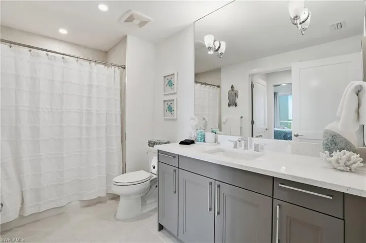 Full bath featuring connected bathroom, vanity, light tile patterned flooring, recessed lighting, and a shower with curtain - Virtually Edited Image