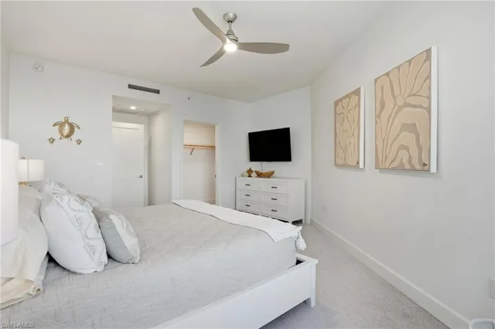 Bedroom featuring light colored carpet, a ceiling fan, and a spacious closet - Virtually Edited Image