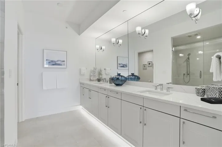 Full bath featuring a stall shower, double vanity, and light tile patterned floors - Virtually Edited Image