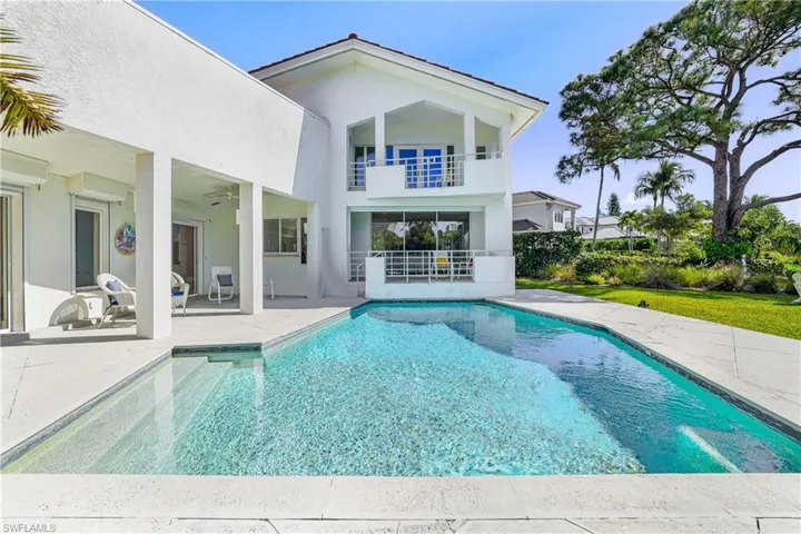 Rear view of house featuring an outdoor pool, stucco siding, a balcony, a patio, and ceiling fan