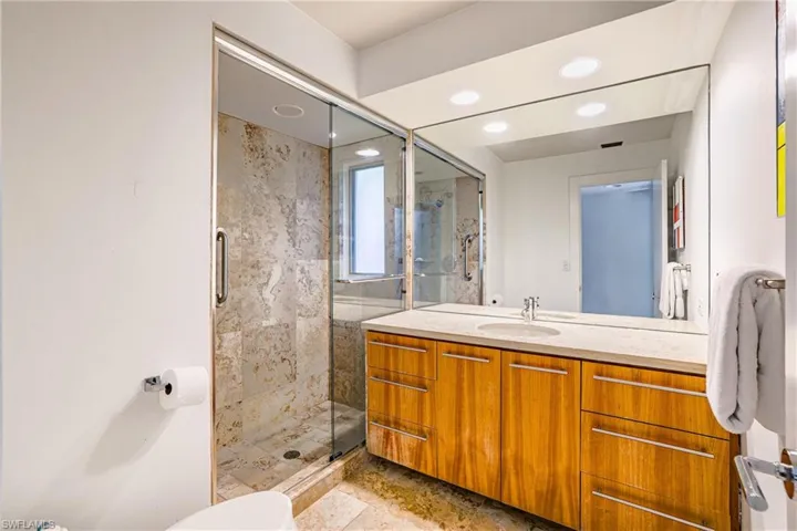 Full bathroom featuring vanity, a marble finish shower, and recessed lighting
