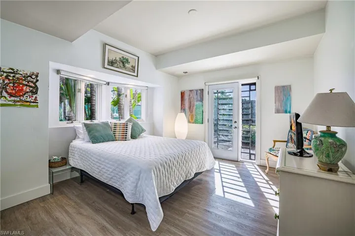 Bedroom featuring french doors, wood finished floors, multiple windows, and access to outside