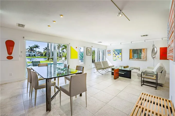 Dining space featuring track lighting, a water view, light tile patterned floors, and french doors