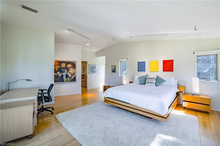 Bedroom with rail lighting, lofted ceiling, light wood-type flooring, and a desk