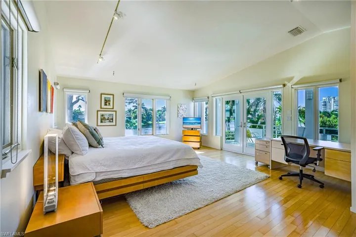 Bedroom with french doors, access to outside, a desk, light wood finished floors, and lofted ceiling