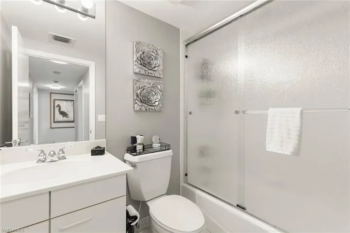 Full bathroom featuring combined bath / shower with glass door, toilet, and vanity