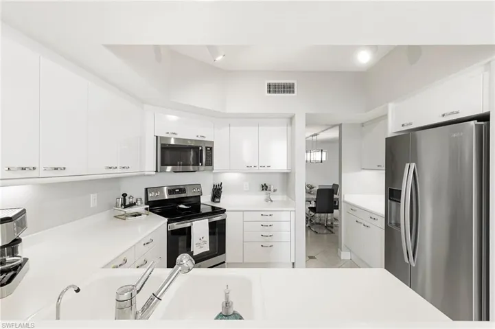 Kitchen with light tile patterned floors, stainless steel appliances, and white cabinetry