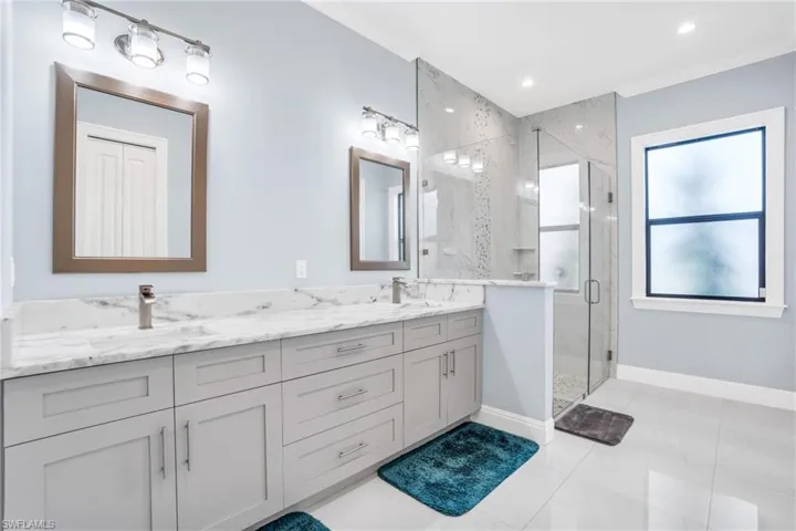 Bathroom with an enclosed shower, tile patterned flooring, dual bowl vanity, and crown molding