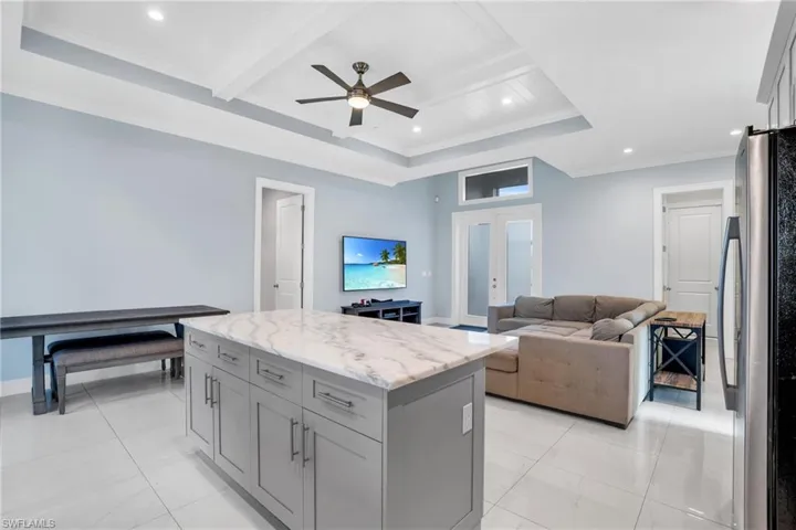 Kitchen with beam ceiling, a tray ceiling, gray cabinets, ceiling fan, and stainless steel fridge