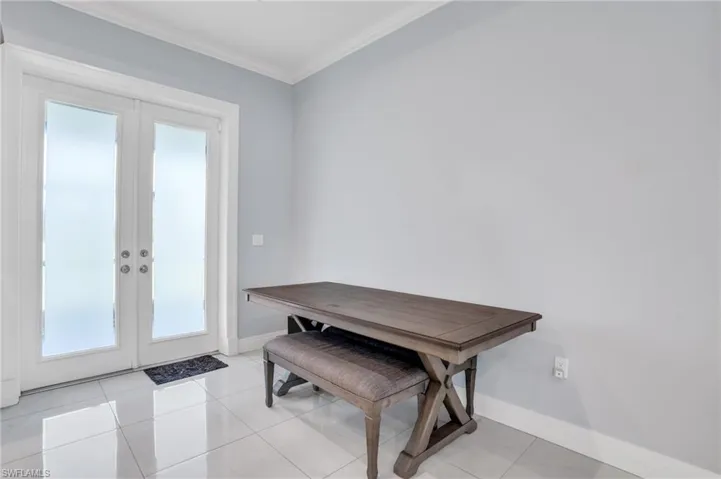 Dining space featuring light tile patterned flooring, crown molding, and french doors