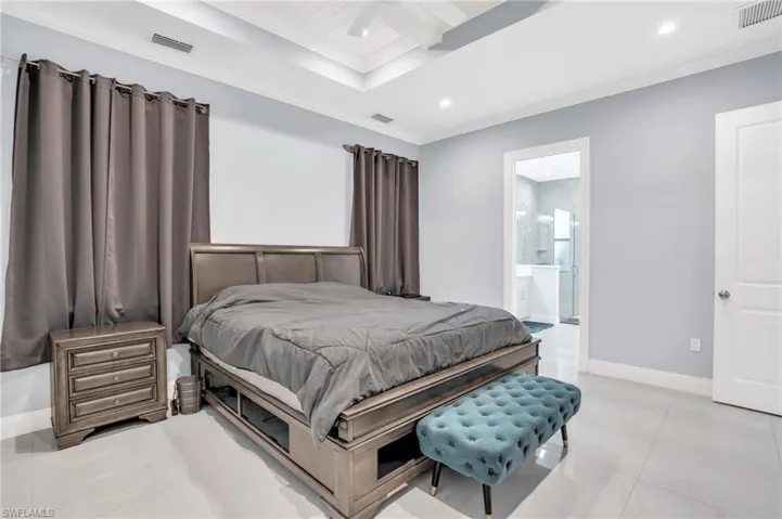Bedroom with ensuite bathroom, ornamental molding, and light tile patterned floors