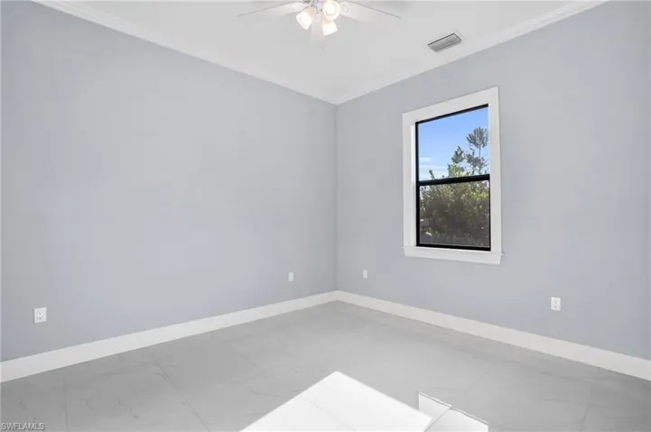 Unfurnished room with ceiling fan, tile patterned floors, and ornamental molding