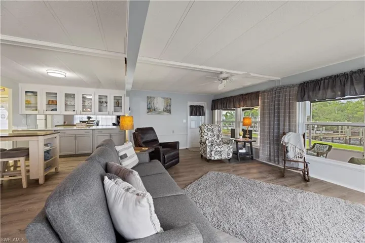 Living room with beam ceiling, vinyl flooring, and ceiling fan