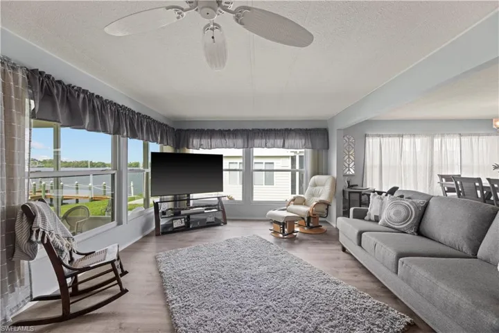 Living room featuring a textured ceiling, ceiling fan, vinyl floors, and a wealth of natural light