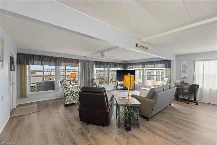Living room featuring ceiling fan, vinyl flooring, and a wealth of natural light