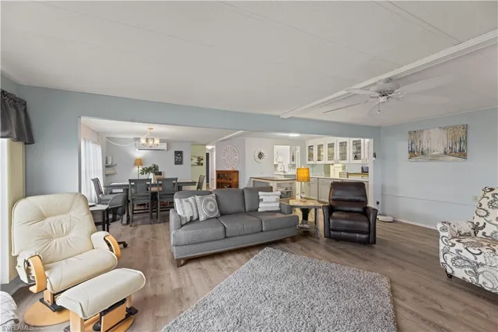 Living room with ceiling fan with notable chandelier and vinyl flooring
