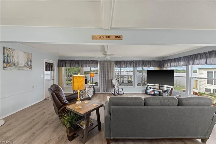 Living room with beamed ceiling, plenty of natural light, and vinyl flooring.