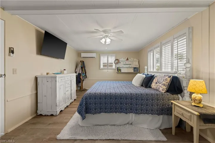 Bedroom featuring hardwood / wood-style flooring, ceiling fan, and a wall mounted air conditioner