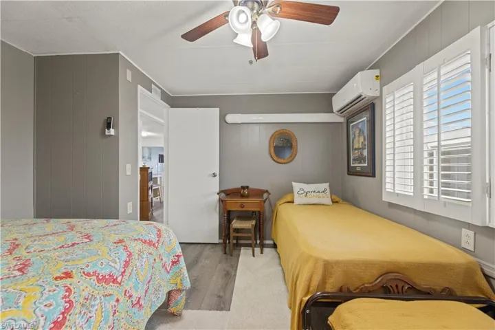 Bedroom featuring ceiling fan, hardwood / wood-style flooring, and a wall mounted AC