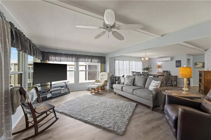 Living room featuring a healthy amount of sunlight, a wall unit AC, ceiling fan, and hardwood / wood-style floors
