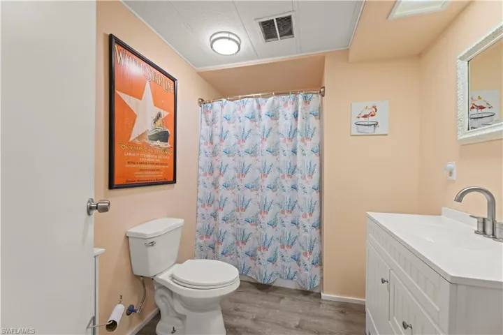 Bathroom with large vanity, wood-type flooring, and toilet