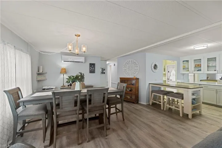 Dining space with a textured ceiling, a chandelier, hardwood / wood-style flooring, and an AC wall unit