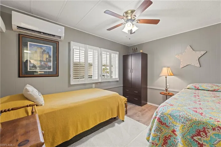 Bedroom featuring a wall unit AC, ceiling fan, and light hardwood / wood-style floors