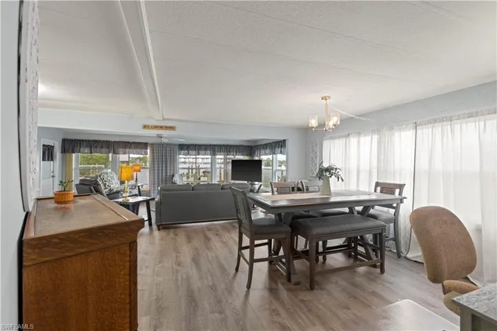 Dining space featuring beamed ceiling, a textured ceiling, a chandelier, and wood-type flooring