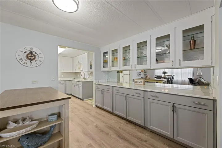 Kitchen with light stone countertops, vinyl flooring, gray cabinets, sink, and a textured ceiling
