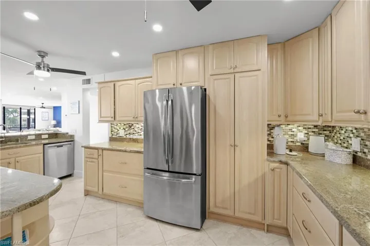 Kitchen with a ceiling fan, light wood finish cabinets, stainless steel appliances, light stone counters, and recessed lighting
