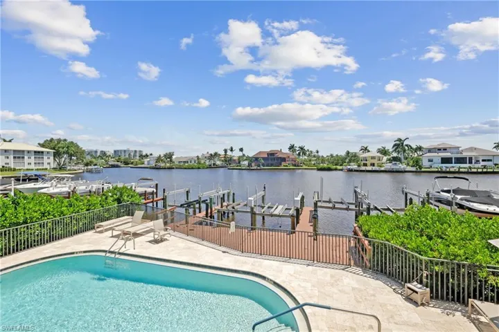 Community pool featuring boat lift, a water view, a dock, and a patio