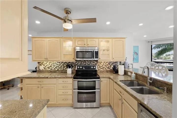 Kitchen featuring stainless steel appliances, light wood finish cabinetry, dark stone counters, and recessed lighting