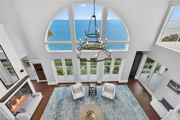 Living area with a glass covered fireplace, a high ceiling, hanging lights, dark wood-type flooring, and a water view