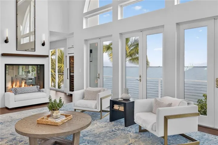 Living area with healthy amount of natural light, wood finished floors, french doors, and a high ceiling