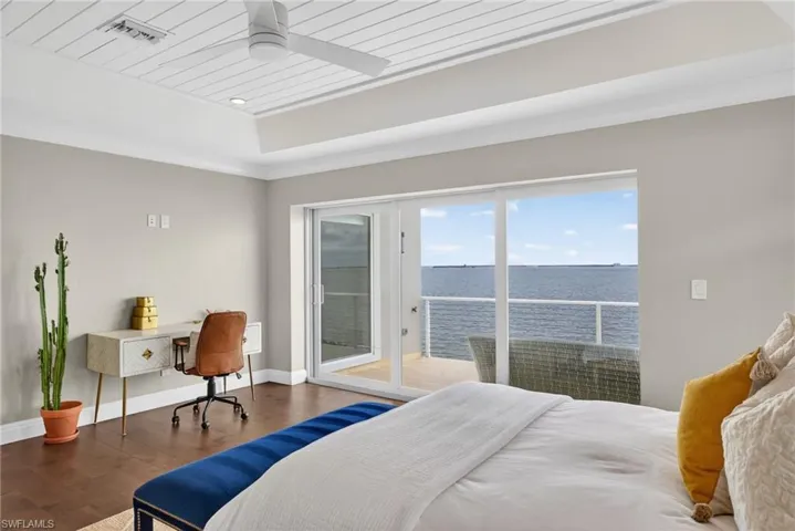 Bedroom featuring a water view, an office area, access to outside, wood finished floors, and ceiling fan