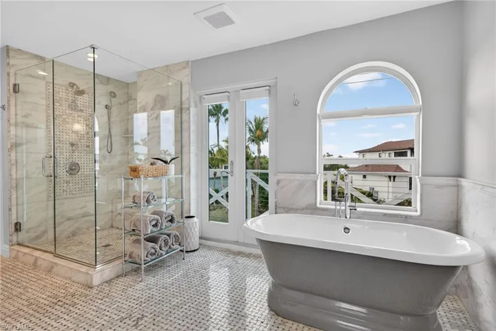 Bathroom with a soaking tub, a shower stall, tile walls, and wainscoting