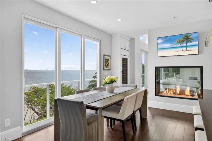 Dining space with dark wood-style flooring, plenty of natural light, wine cooler, and recessed lighting