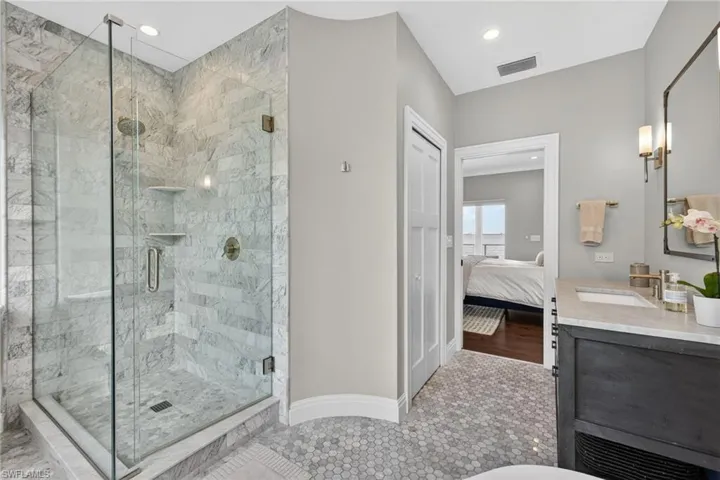 Ensuite bathroom featuring a marble finish shower, vanity, and recessed lighting