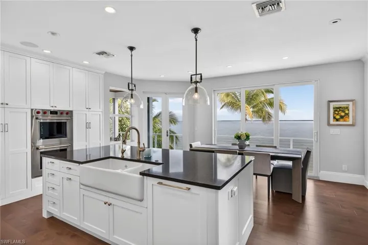 Kitchen featuring white cabinetry, dark wood finished floors, pendant lighting, and a center island with sink