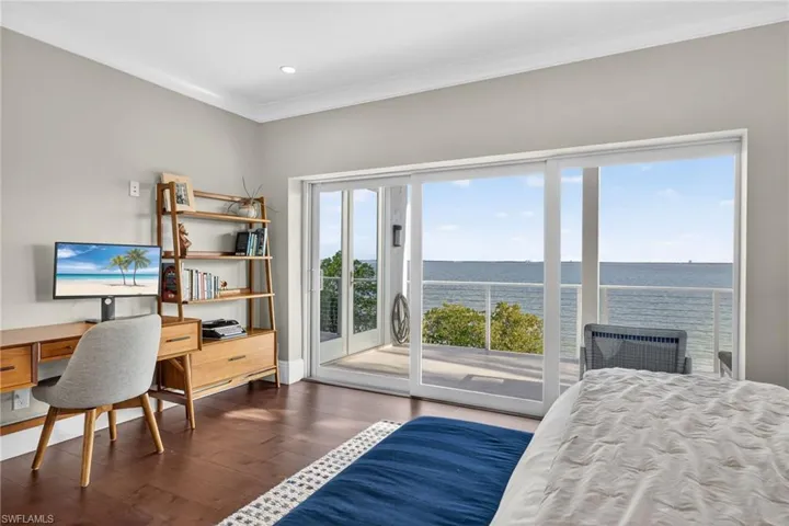 Bedroom featuring a water view, ornamental molding, an office area, access to exterior, and dark wood finished floors