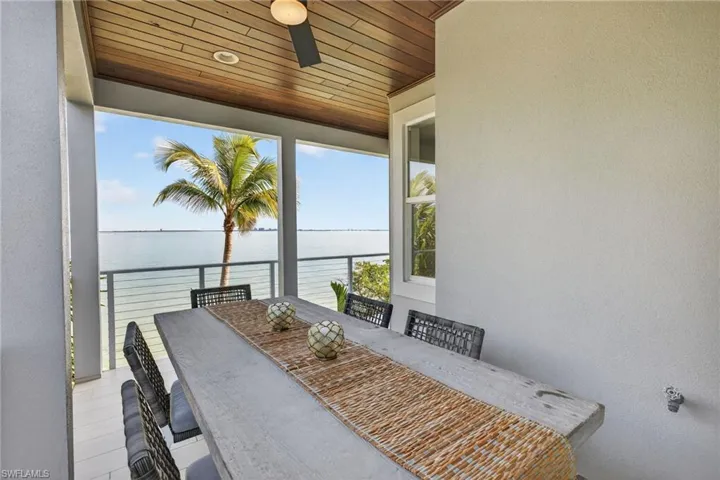 View of patio featuring outdoor dining space, a water view, and a ceiling fan