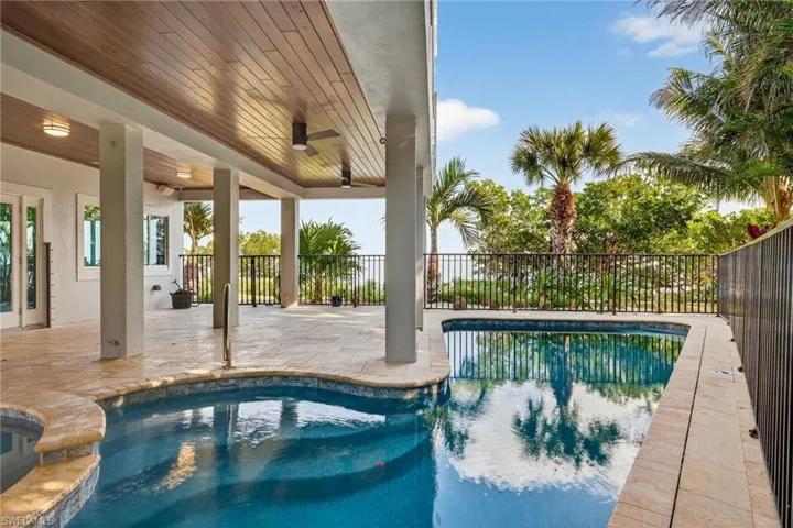 View of swimming pool featuring patio surround and an in-ground hot tub