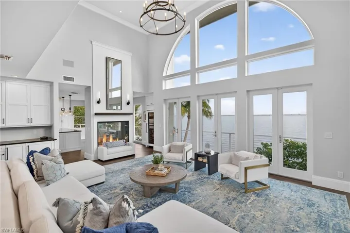 Living area featuring a chandelier, a water view, dark wood-type flooring, crown molding, and a high ceiling