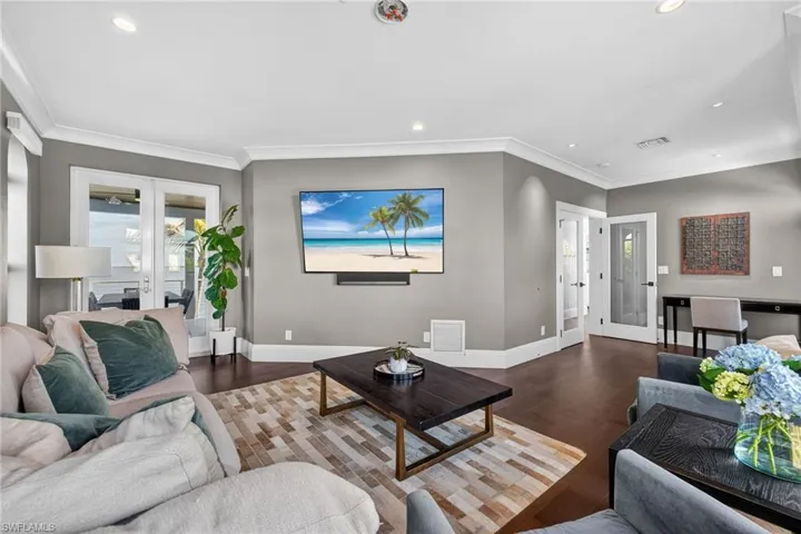 Living room featuring french doors, ornamental molding, recessed lighting, wood finished floors, and an office area