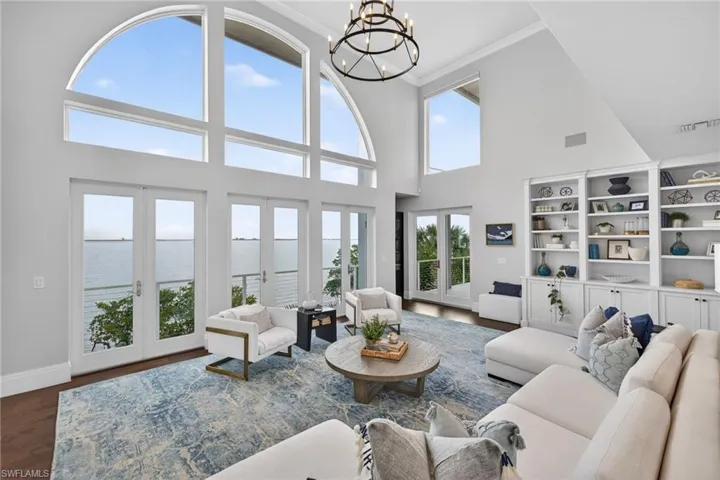 Living area with a water view, hanging lights, french doors, wood finished floors, and a high ceiling