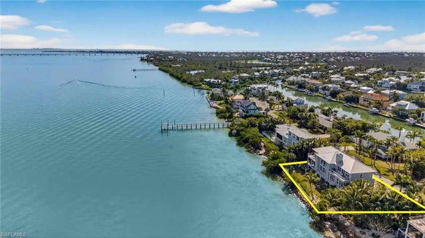 Aerial perspective of suburban area featuring a large body of water and property boundaries highlighted