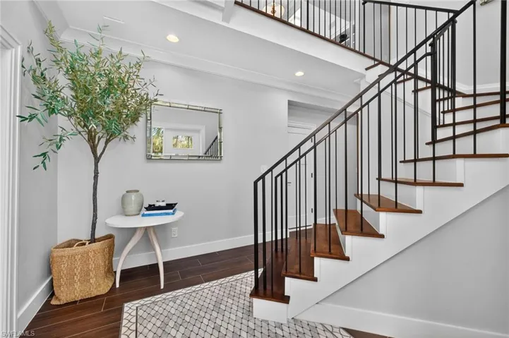 Staircase with wood finished floors and recessed lighting