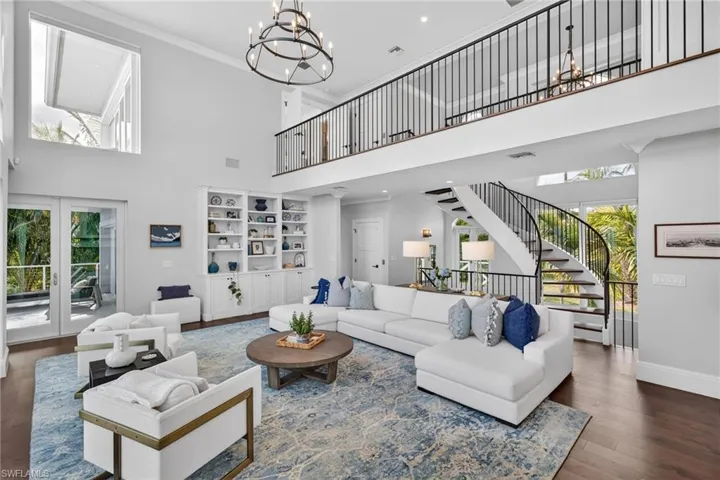 Living room with hanging lights, hardwood / wood-style floors, a high ceiling, and crown molding